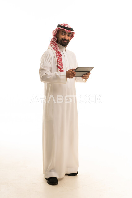 رجل سعودي بالزي التقليدي يحمل جهازاً لوحياً