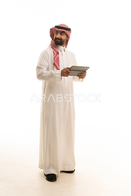 رجل سعودي بالزي التقليدي يحمل جهاز لوحي
