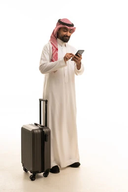 رجل سعودي مع حقيبة سفر يستخدم الهاتف الذكي