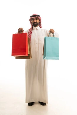 رجل سعودي يحمل أكياس تسوق ملونة في استوديو