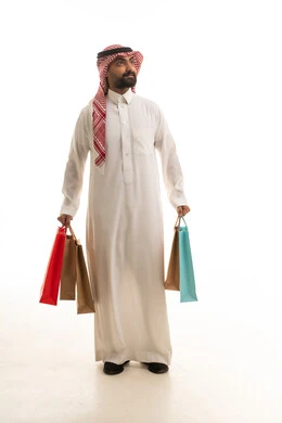 رجل سعودي يحمل أكياس تسوق على خلفية بيضاء