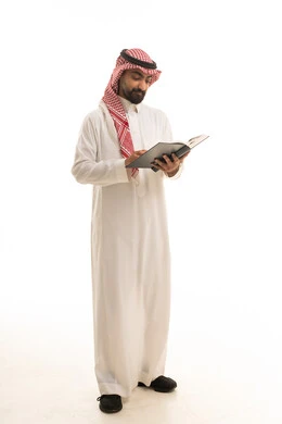 رجل سعودي بالزي التقليدي يقرأ كتاباً في الاستوديو