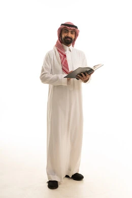 رجل سعودي باللباس التقليدي يمسك كتاباً في الاستوديو