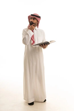 رجل سعودي باللباس التقليدي يقرأ كتابا