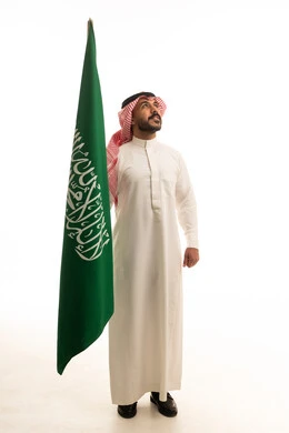رجل سعودي يحمل العلم الوطني على خلفية بيضاء