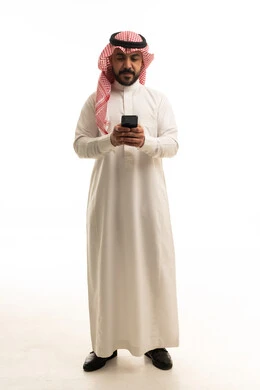 رجل سعودي بالزي التقليدي يستخدم الهاتف الذكي في الاستوديو