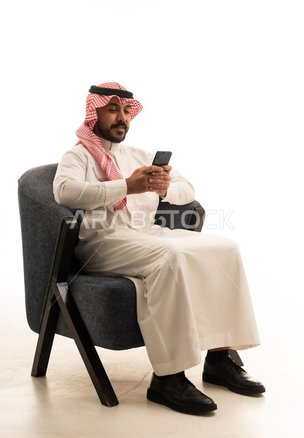 Saudi Man in Traditional Thobe Using Smartphone