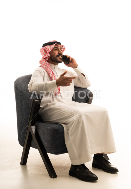 رجل سعودي يرتدي الثوب التقليدي يتحدث عبر الهاتف المحمول