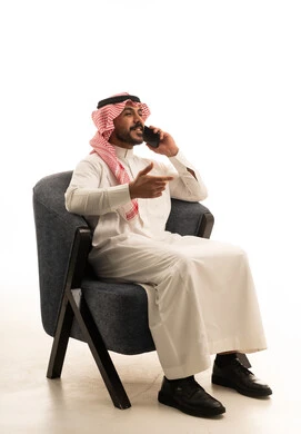 رجل سعودي يرتدي الثوب التقليدي يتحدث عبر الهاتف المحمول
