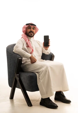 رجل سعودي بالزي التقليدي يمسك هاتف ذكي