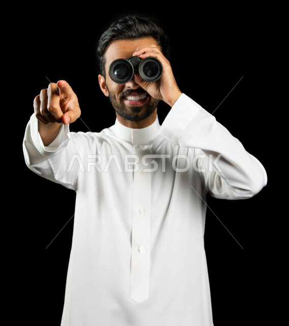 رجل عربي خليجي سعودي يرتدي الزي السعودي التقليدي ، يحمل بيده المنظار ثنائي العينين ( التلسكوب )، إيماءات وجه ويدين مختلفة ، الناظور، الاستكشاف والمغامرة ، خلفية سوداء، رؤية مستقبلية ، أهداف وطموحات ، التخطيط المستقبلي
