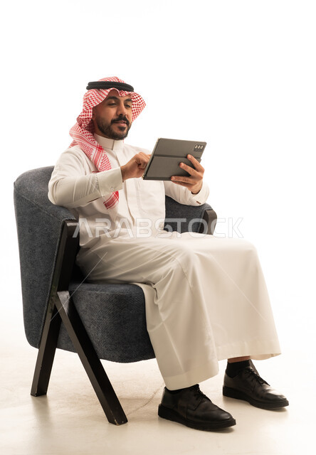 Saudi Man in Traditional Dress Using Tablet on White