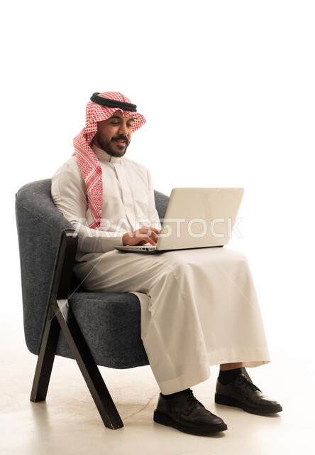 رجل سعودي بالزي التقليدي يستخدم الحاسوب المحمول