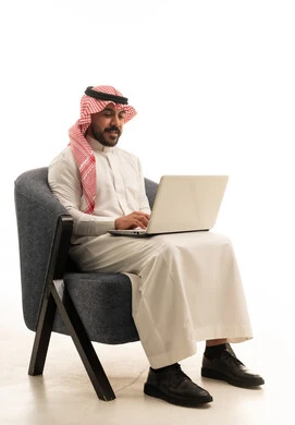 رجل سعودي بالزي التقليدي يستخدم الحاسوب المحمول