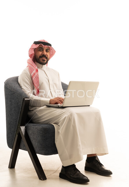 رجل سعودي بالزي التقليدي يستخدم جهاز كمبيوتر محمول