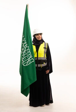 مهندسة سعودية تحمل العلم الوطني بخلفية بيضاء