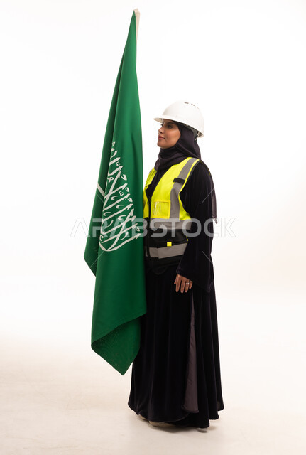مهندسة سعودية مع العلم الوطني بملابس السلامة