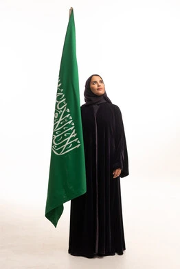 امرأة سعودية بالعباءة السوداء مع العلم الوطني في الاستوديو
