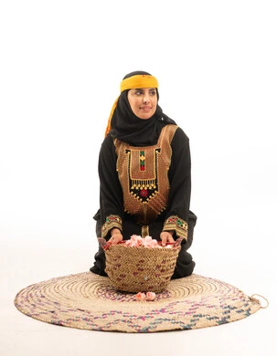 امرأة سعودية بالزي التقليدي مع سلة من الورد