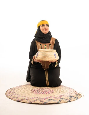 امرأة سعودية بالزي التراثي مع سلة خوص