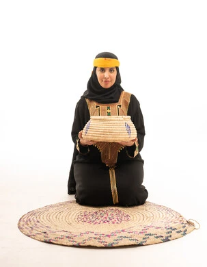 امرأة إماراتية بالزي التقليدي تحمل سلة خوص