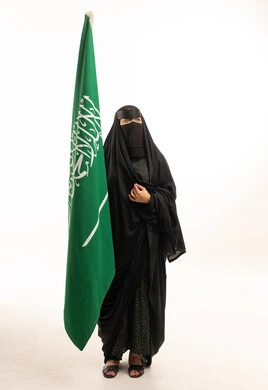 امرأة سعودية بالنقاب تحمل علم المملكة العربية السعودية