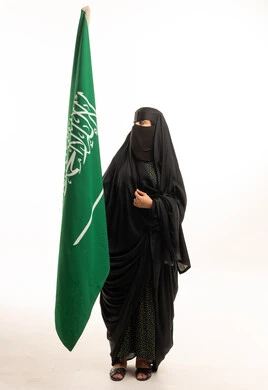 امرأة سعودية بالنقاب مع علم المملكة العربية السعودية