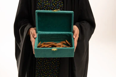 امرأة سعودية تحمل صندوق بخور عود أخضر مفتوح