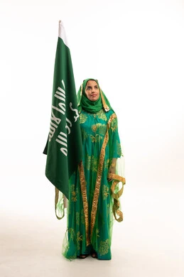 امرأة سعودية تحمل العلم الوطني بالثوب التقليدي