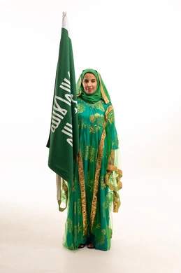امرأة سعودية تحمل العلم بالثوب التقليدي الأخضر