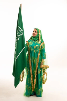 امرأة سعودية ترتدي ثوب النشل التقليدي مع العلم الوطني