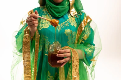 امرأة إماراتية بالزي التقليدي تحمل مرطبان عسل