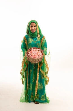 امرأة سعودية بالزي التقليدي الأخضر تحمل سلة ورد