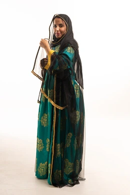 سعودية بالزي التقليدي والجلابية الخضراء والعباءة السوداء