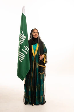 فتاة سعودية بالزي التقليدي مع العلم الوطني