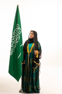 امرأة سعودية مع العلم الوطني باللباس التقليدي