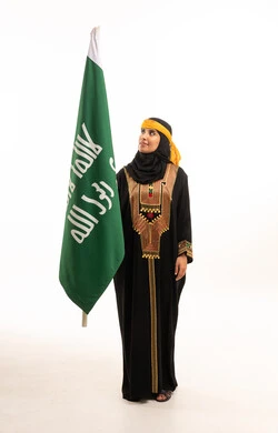 امرأة سعودية بالزي الشعبي التراثي مع علم السعودية