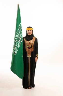 امرأة سعودية مع العلم بالعباءة التقليدية