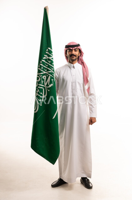 رجل سعودي بالزي التقليدي يحمل علم المملكة
