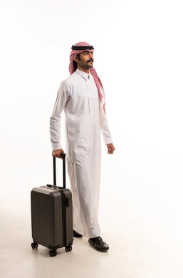 رجل سعودي بالزي التقليدي يمشي مع حقيبة سفر
