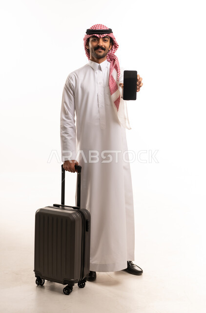 رجل سعودي مع حقيبة سفر وهاتف ذكي خلفية بيضاء