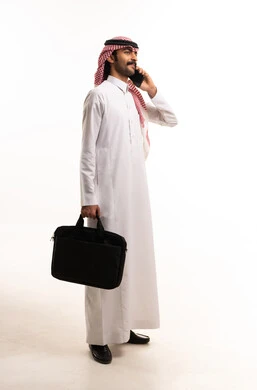 رجل أعمال سعودي بالثوب التقليدي يتحدث بالهاتف الذكي
