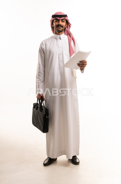 رجل أعمال سعودي بالزي التقليدي يحمل حقيبة وأوراق