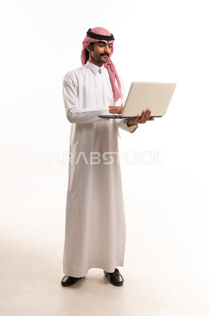 رجل سعودي بالزي التقليدي يستخدم المحمول في الاستوديو