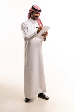 رجل سعودي بالزي التقليدي يكتب على ورقة