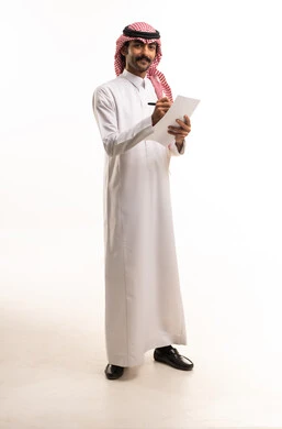 رجل أعمال سعودي بالزي التقليدي يكتب على ورقة في استوديو