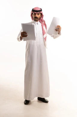 Saudi Man in Traditional Dress Reading Documents