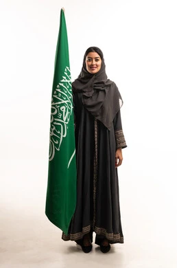 امرأة سعودية بالعباءة مع علم المملكة العربية السعودية