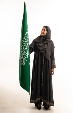 Saudi Woman in Traditional Abaya Holding Saudi Flag