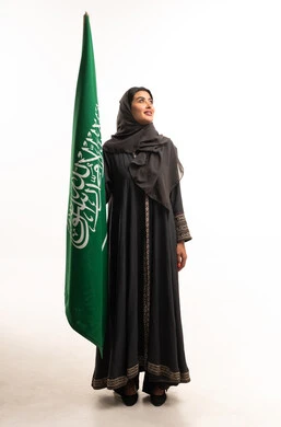 امرأة سعودية تحمل علم المملكة العربية السعودية في استوديو